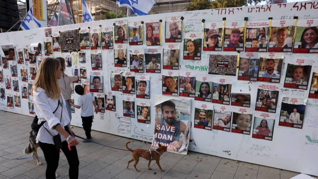 People look at an installation which shows the pictures of hostages taken by Palestinian Islamist group Hamas following a deadly infiltration of Israel by Hamas gunmen from the Gaza Strip on October 7, before some of them are due to be released as part of a deal between Israel and Hamas to free hostages held in Gaza in exchange for the release of Palestinian prisoners, in Tel Aviv, Israel, November 24, 2023
